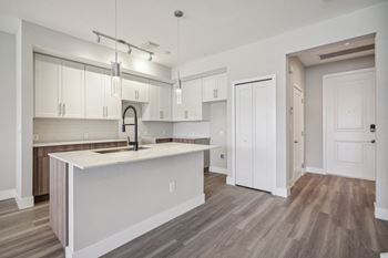 an open kitchen and living room with white cabinets and a white counter top at The Falls of Portofino Apartment, Florida